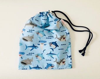 Waterproof bag for wet swimsuits in sky blue coated fabric with little shark patterns.