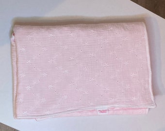 Baby blanket in white cotton double gauze fabric embroidered with light floral patterns, pink minky fabric and a layer of warm fleece.
