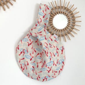 Wendbare japanische Tasche aus Baumwollstoff, bedruckt mit kleinen roten Fischmustern, gefüttert mit cremefarbenem Leinenstoff.