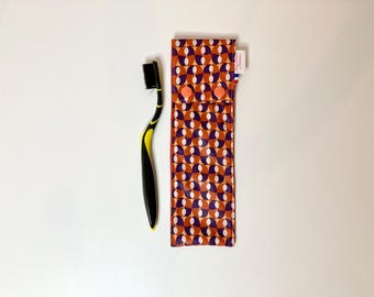 Waterproof toothbrush pouch in coated fabric with orange and purple geometric patterns and orange interior.