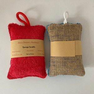 May include: Two reusable cleaning sponges. One is red and made of terry cloth with a loop handle. The other is brown and made of burlap with a white string handle. Both have labels that say "Sous-Cuisson - Printemps" and "Eponge lavable".