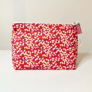 Piccola trousse in tessuto liberty rosa fucsia con piccoli fiori bianchi.