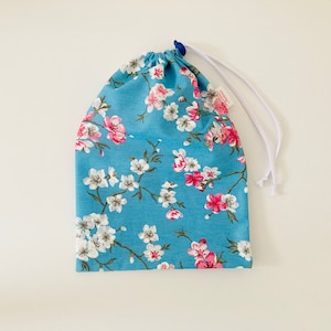 Wasserdichte Tasche für nasse Badeanzüge aus blau beschichtetem Baumwollstoff mit japanischen Kirschblütenmustern in Weiß und Rosa