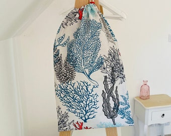 Grand Sac imperméable pour le linge sale ou mouillé beige avec des motifs marins multicolores.