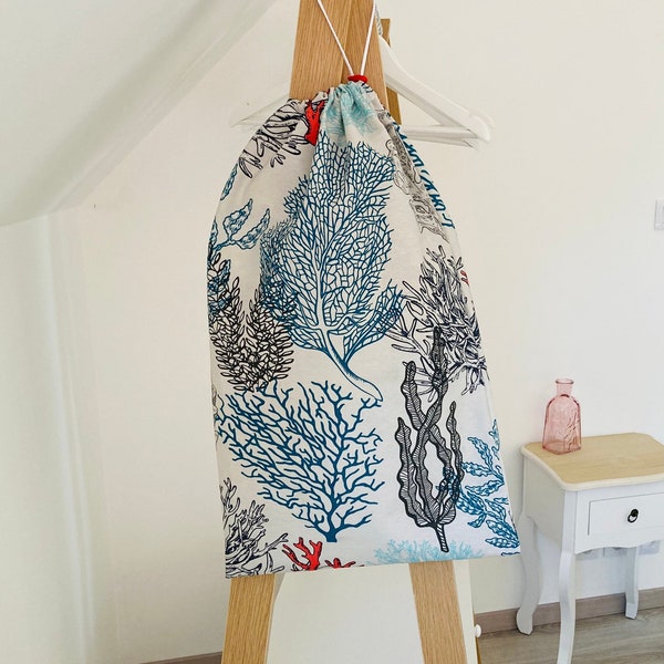 Grand Sac imperméable pour le linge sale ou mouillé beige avec des motifs marins multicolores.