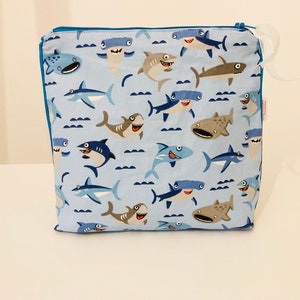 Toiletry bag in sky blue coated fabric with small shark patterns, lined in white coated linen