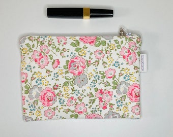 Small makeup bag in white fabric with pink patterns in pale pink and pearl gray colors.
