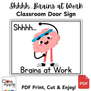 Op de afbeelding: Een bord voor de klasdeur met de tekst "Shhhh...Brains at Work". Het bord toont een cartoon hersenkarakter met een blauwe zweetband en sneakers. Het bord is wit met zwarte tekst en een roze hersen.