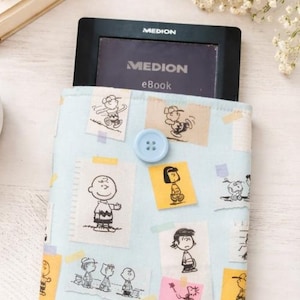 Può includere: Una custodia per ebook azzurra con illustrazioni di personaggi dei cartoni animati. La custodia ha una chiusura con bottone azzurro. Il dispositivo ebook all'interno della custodia mostra il testo "MEDION eBook".