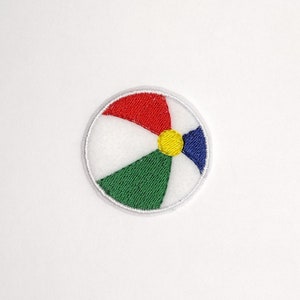 May include: A white, red, green, blue, and yellow embroidered patch of a beach ball.