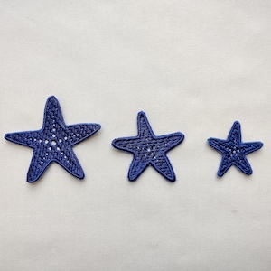 May include: Three blue fabric starfish of varying sizes. The largest starfish is on the left, the medium-sized starfish is in the center, and the smallest starfish is on the right.