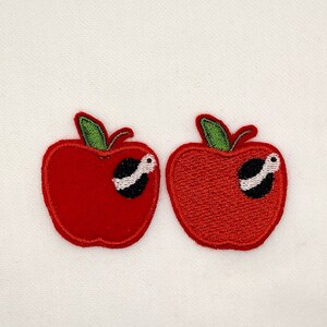 May include: Two red felt apple patches with green stems and a black and white worm inside each apple.