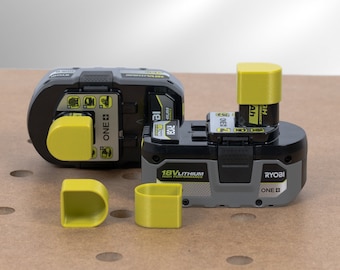 May include: Two gray and yellow Ryobi 18V lithium-ion batteries with a yellow battery cap on each. The batteries are on a brown wooden surface with holes.