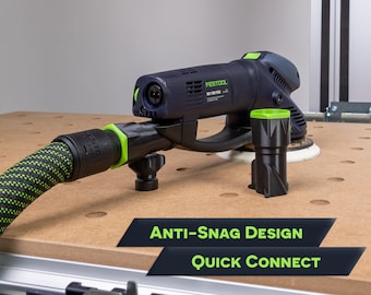 May include: A black and green power sander with a hose attachment. The sander has a green and black quick connect hose attachment. The sander has the text "FESTOOL" and "RO 150 FEQ" on it. The sander is on a wooden surface with a pegboard design. The text "ANTI-SNAG DESIGN" and "QUICK CONNECT" is on the surface.