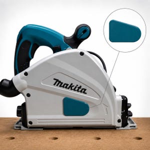 May include: A Makita plunge saw featuring a light gray housing with teal accents and a black handle. The tool displays the Makita brand name in black text on the side. A circular inset shows a magnified view of a small, teal, trapezoidal component.