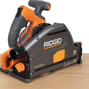 Puede incluir: Una sierra circular Ridgid gris y naranja con motor sin escobillas. La sierra est&aacute; sobre una superficie de madera.