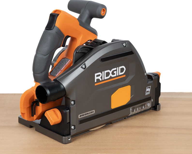 Puede incluir: Una sierra circular Ridgid gris y naranja con motor sin escobillas. La sierra est&aacute; sobre una superficie de madera.