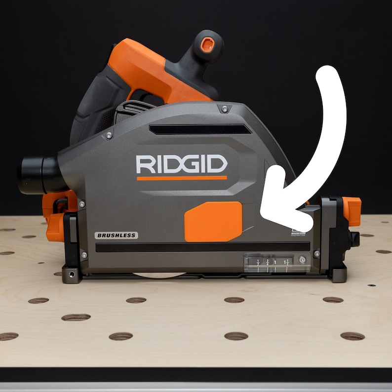 Puede incluir: Una sierra circular gris y naranja con un mango negro y la palabra "RIDGID" impresa en el lateral. La sierra est&aacute; sobre una superficie de madera con agujeros.