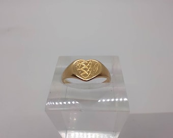 May include: A gold heart-shaped signet ring with an engraved design.