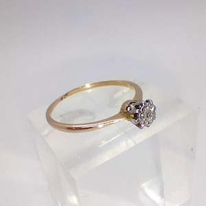 May include: A delicate gold band ring with a single, small, round diamond set in the centre.