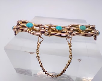 May include: A gold-toned bracelet with a series of interconnected, wavy links. Each link is adorned with small, round, turquoise-colored stones. A delicate gold chain is attached for added security. The bracelet is displayed on a clear, angled surface.