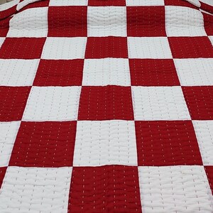 Modern bedroom décor featuring red and white cotton quilt.