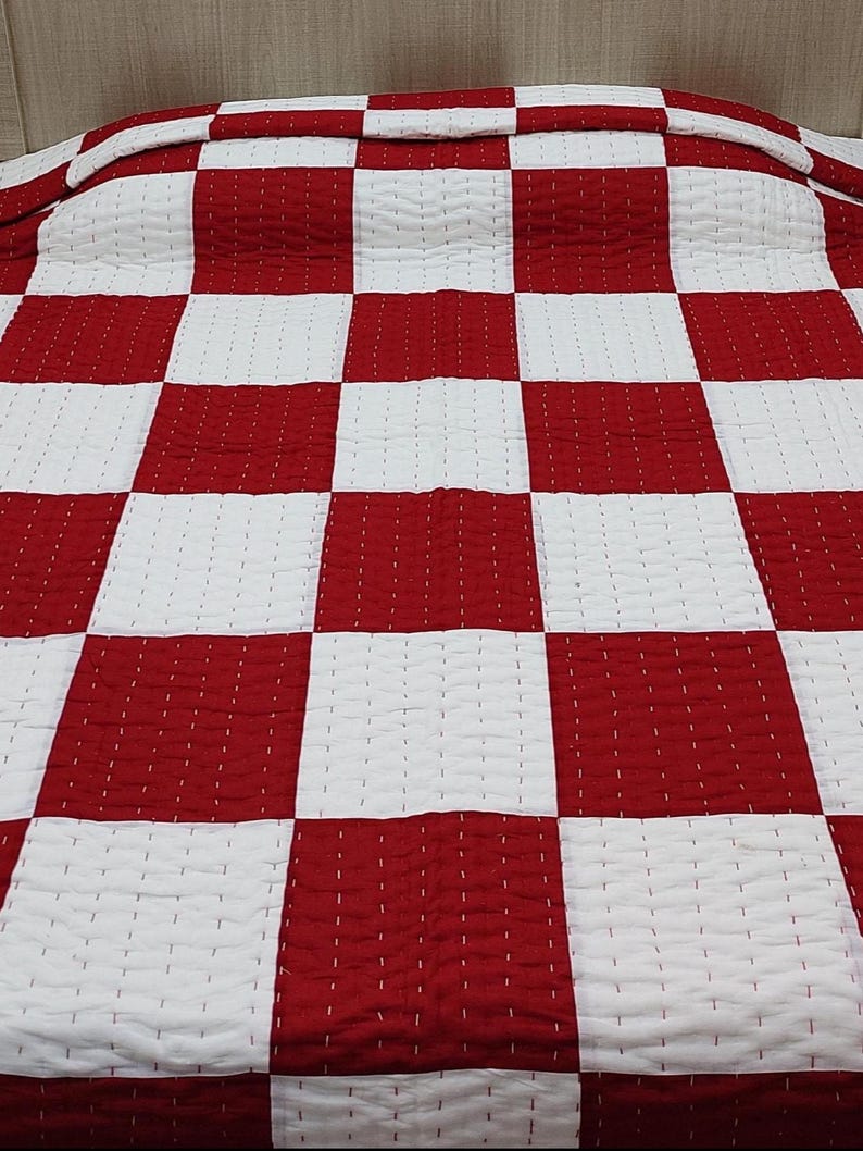 Modern bedroom décor featuring red and white cotton quilt.
