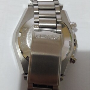May include: A silver wristwatch with a stainless steel band and a silver case. The watch has a chronograph function and the word "SEIKO" is engraved on the back.