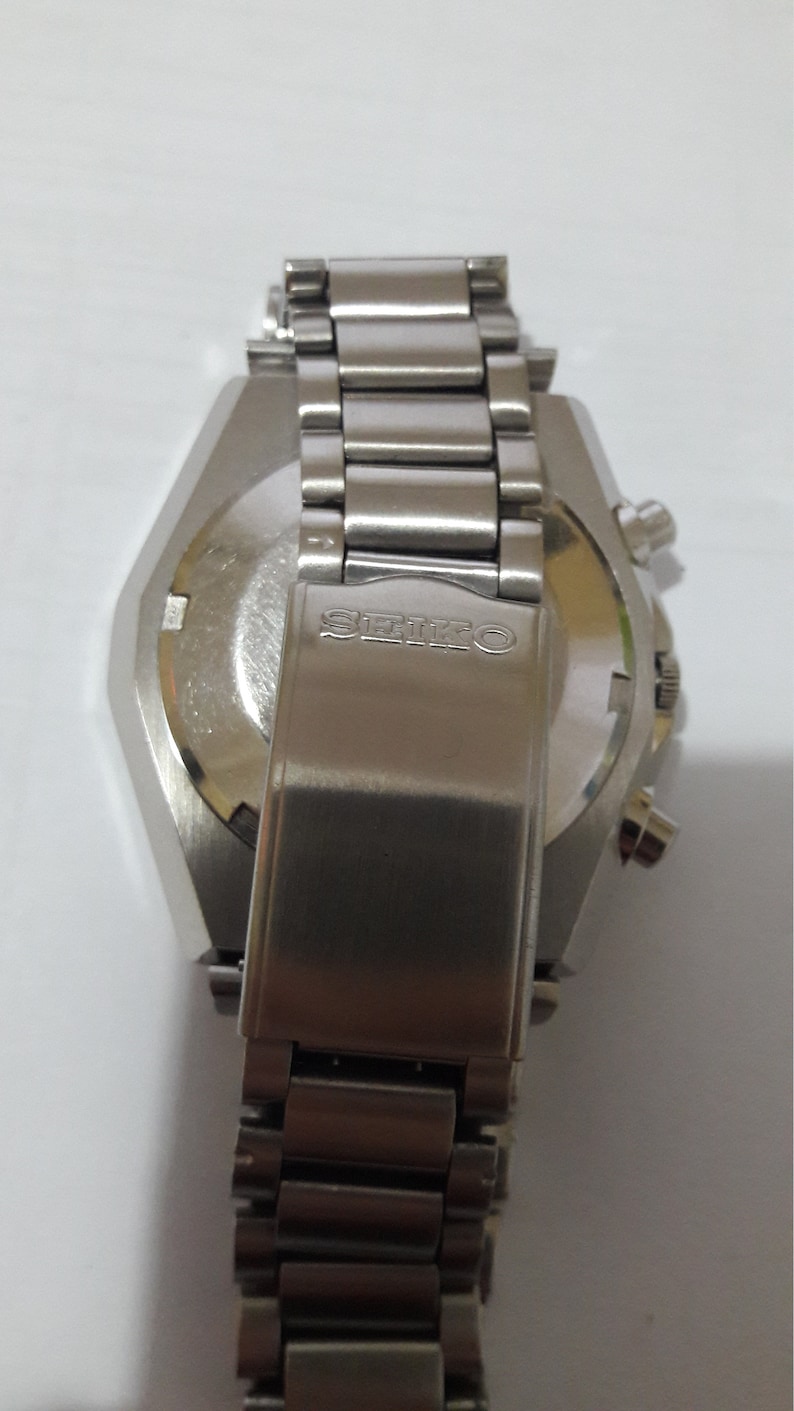 May include: A silver wristwatch with a stainless steel band and a silver case. The watch has a chronograph function and the word "SEIKO" is engraved on the back.