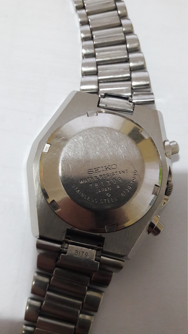 May include: Silver Seiko wristwatch with a stainless steel band. The back of the watch has the text "SEIKO WATER RESISTANT 781309 JAPAN A 6139-7030 STAINLESS STEEL".