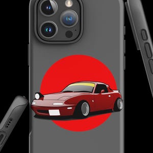 Peut inclure: Une coque de téléphone grise avec un cercle rouge et une voiture de sport rouge au centre. La coque de téléphone a une découpe pour l'objectif de l'appareil photo et un côté noir.
