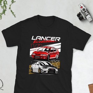 Op de afbeelding: Zwart T-shirt met een afbeelding van twee rode en witte Mitsubishi Lancer Evolution auto's. De tekst "LANCER Evolution VI" is boven de auto's gedrukt.