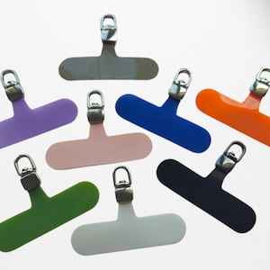 Peut inclure: Assortiment de huit porte-clés en plastique colorés avec des clips en métal argenté. Chaque porte-clés a la forme d'un petit rectangle plat aux coins arrondis.