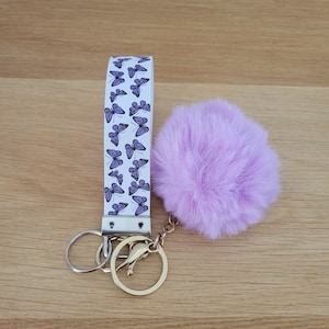 Muñequera con llavero Pom Pom, llavero de pulsera de piel sintética, cordón de muñeca, llavero de coche morado y blanco, correa de muñeca, patrón de mariposa