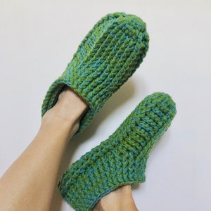 May include: A pair of green and blue crocheted slippers. The slippers are made with a textured stitch and have a simple, comfortable design.
