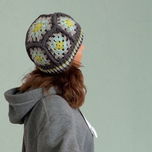 May include: A grey crocheted beanie with a geometric pattern in shades of blue, green, and yellow.