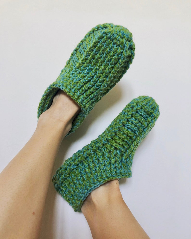 May include: A pair of green and blue crocheted slippers. The slippers are made with a textured stitch and have a simple, comfortable design.