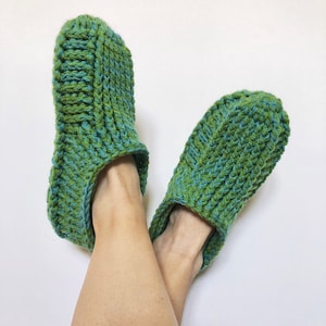 May include: A pair of green and blue crocheted slippers. The slippers are made with a thick yarn and have a simple design.
