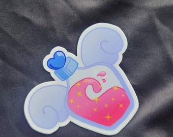 Op de afbeelding: Een sticker met een drankfles met roze hartvormige vloeistof en gele steraccenten. De fles heeft een blauwe hartvormige stopper en is omgeven door lichtblauwe wolkvormige vormen.