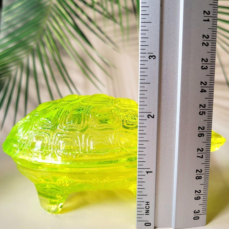 May include: A bright yellow glass turtle trinket box with a detailed shell design. The box is approximately 2.5 inches long.