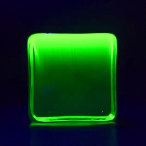 Puede incluir: Un objeto rectangular verde ne&oacute;n brillante con esquinas redondeadas. El objeto est&aacute; iluminado sobre un fondo azul oscuro, creando un efecto visual vibrante y llamativo.