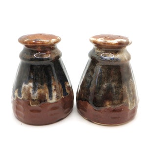 May include: A set of two brown and blue ceramic salt and pepper shakers with a textured glaze.