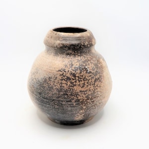 May include: A round, brown ceramic vase with a speckled glaze. The vase has a slightly flared opening and a rounded bottom.