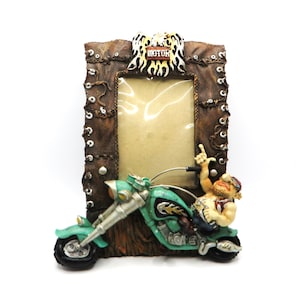 May include: A brown leather picture frame featuring a motorcycle and a man riding it. The frame has a metal eagle with the word "MOTOR" on it.