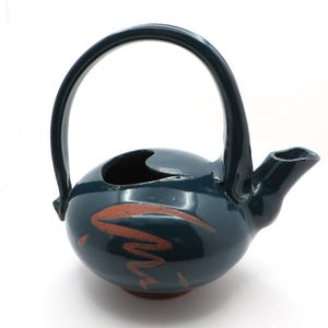 May include: A teal blue ceramic teapot with a brown handle and a brown design on the side. The teapot has a spout on the side and a small opening on the top.