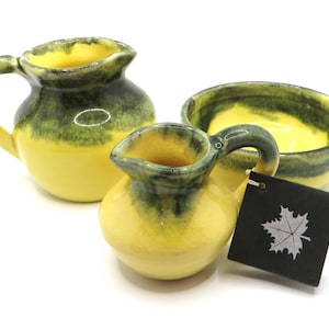 May include: Set of three yellow and green ceramic kitchenware pieces. A small pitcher, a larger pitcher, and a bowl. The pieces are glazed in a yellow and green color scheme.