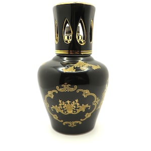May include: Black ceramic oil burner with a gold-colored design. The burner has a decorative top with cut-out details.