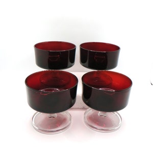 May include: Set of four red glass dessert dishes with clear glass stems. The dishes are round and have a smooth, polished finish.