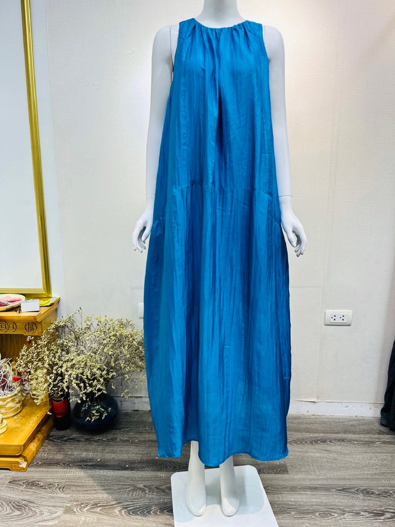 May include: A sleeveless maxi dress in a vibrant blue color. The dress has a loose, flowing fit and a simple, elegant design.