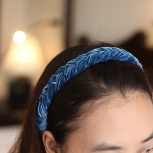 May include: A blue velvet braided headband for women. The headband is made of soft, comfortable material and is perfect for adding a touch of elegance to any outfit.